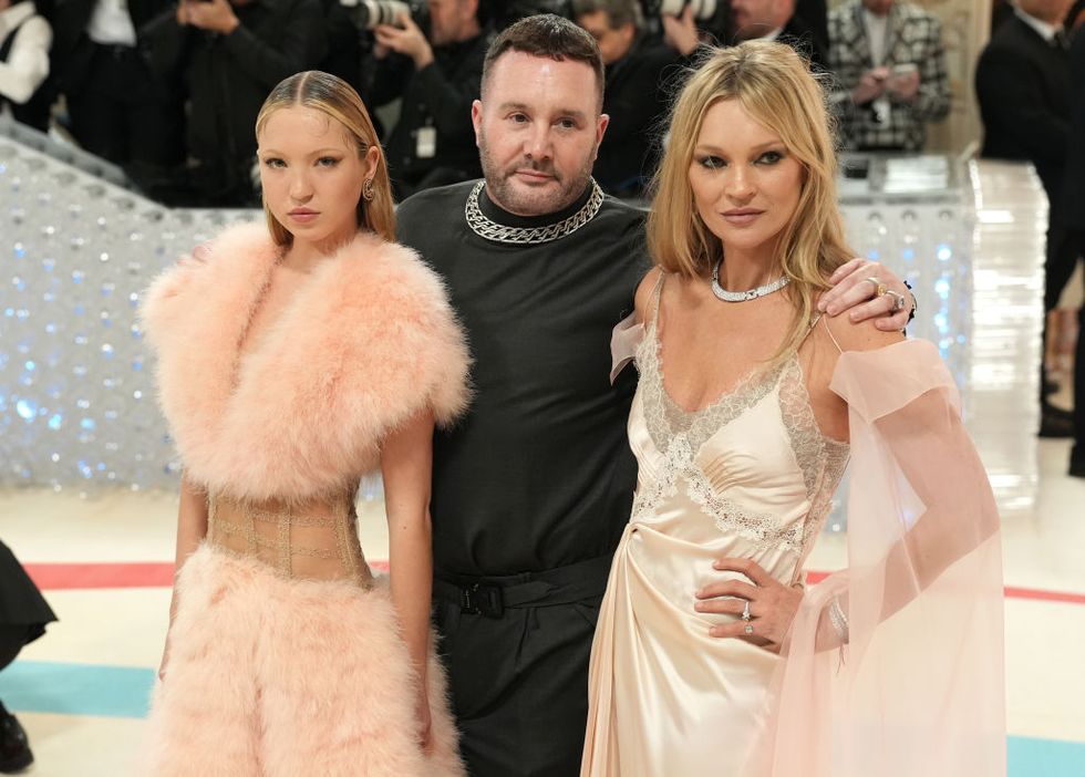 a man posing between two blond women on the red carpet