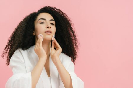Woman applying skincare product to face in bathroom mirror