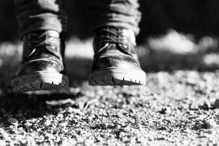 Close-up of black utility boots worn with fashionable clothing on urban street