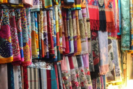 Colorful silk designer scarves arranged displaying various patterns and luxury brand designs