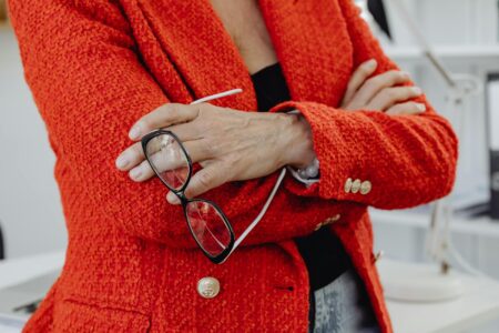 How School Uniform Aesthetics Conquered Adult Fashion Professional navy blazer with brass buttons hanging on clothing rack, showing classic uniform-inspired tailoring details