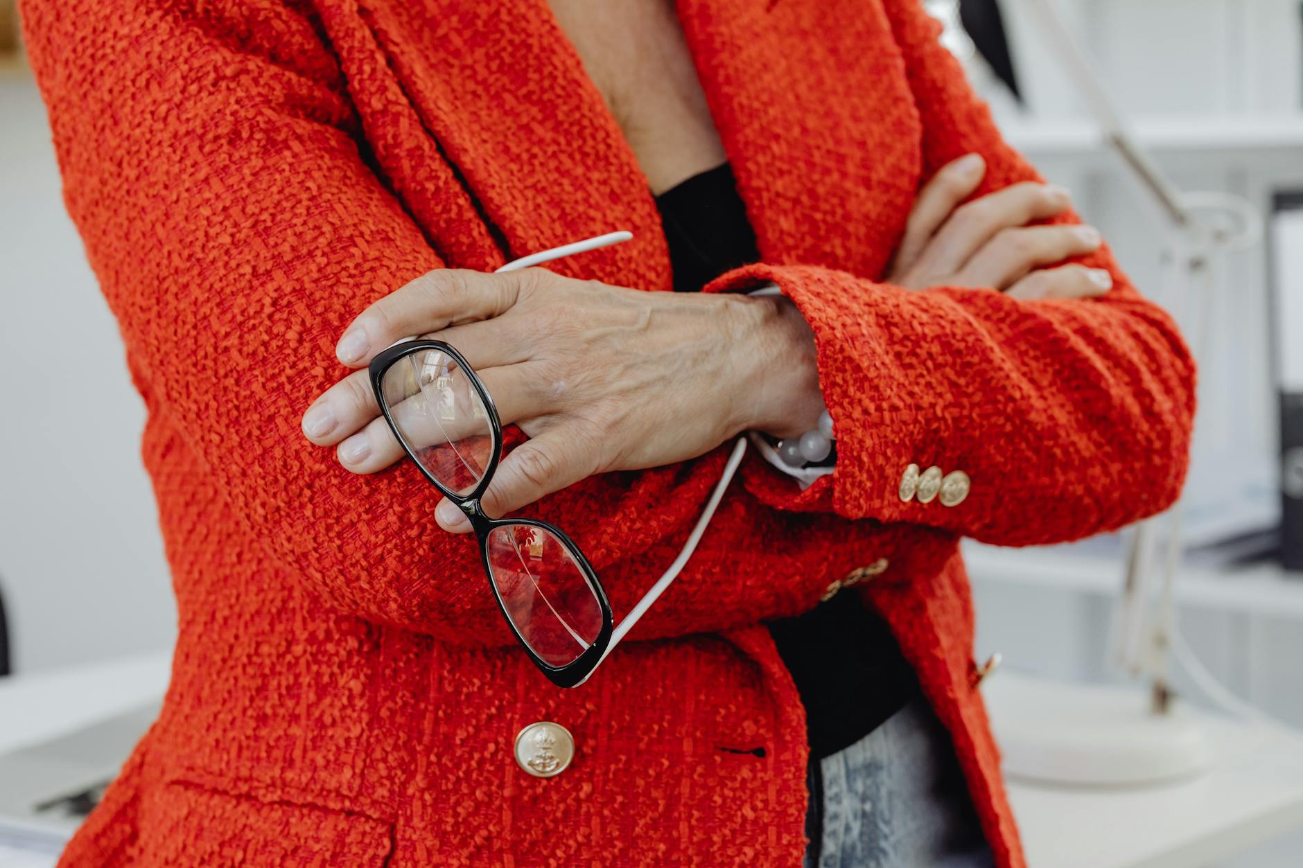 Professional navy blazer with brass buttons hanging on clothing rack, showing classic uniform-inspired tailoring details