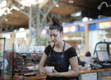 Person wearing a minimalist canvas apron while working behind a coffee counter
