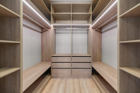 Minimalist closet with systematically organized clothing hanging in neutral colors