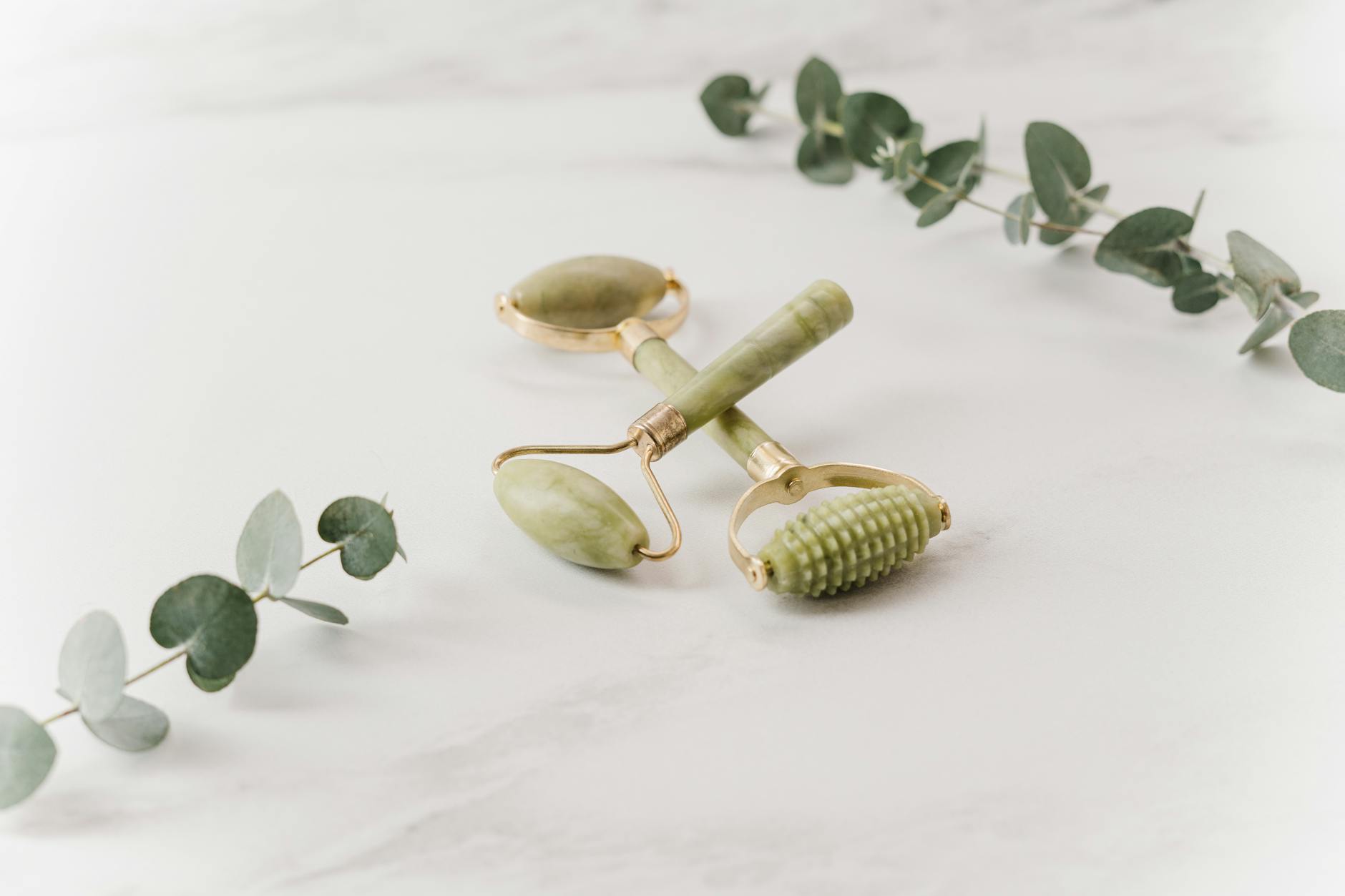 Green jade facial roller on white background showing smooth stone surface