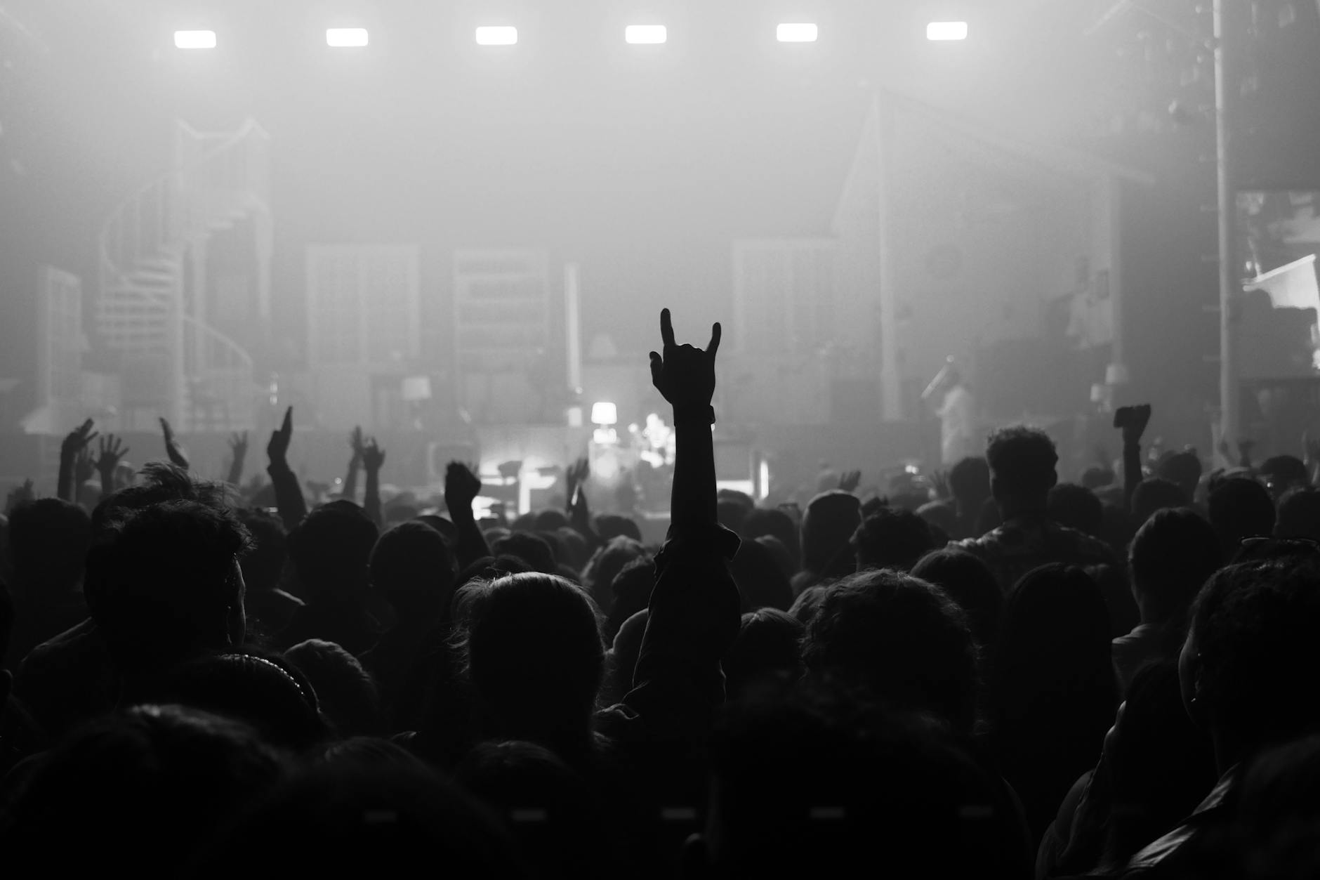 Concert crowd at live music venue with fans wearing band t-shirts and merchandise
