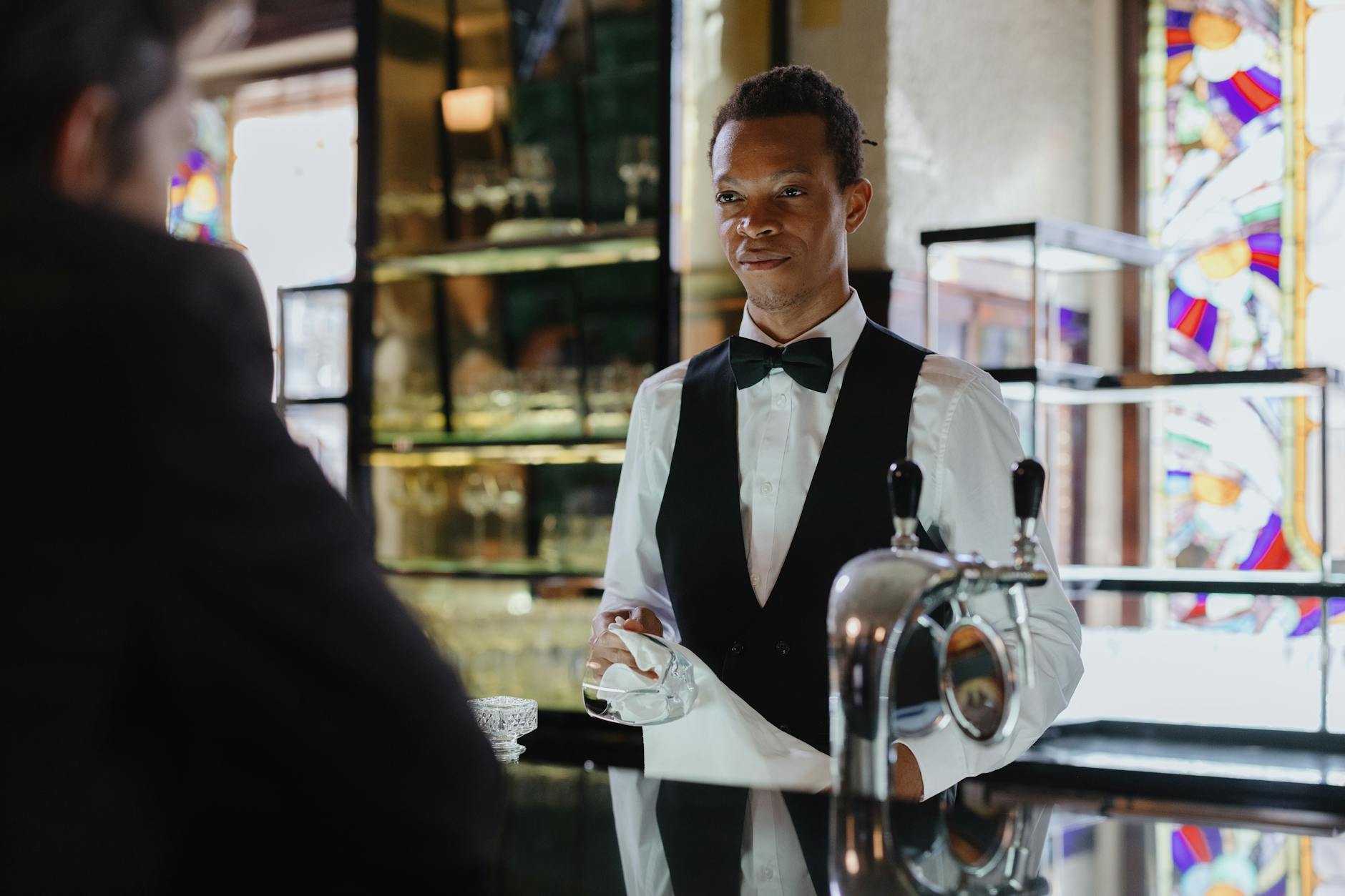 Server in stylish black uniform taking order in upscale restaurant