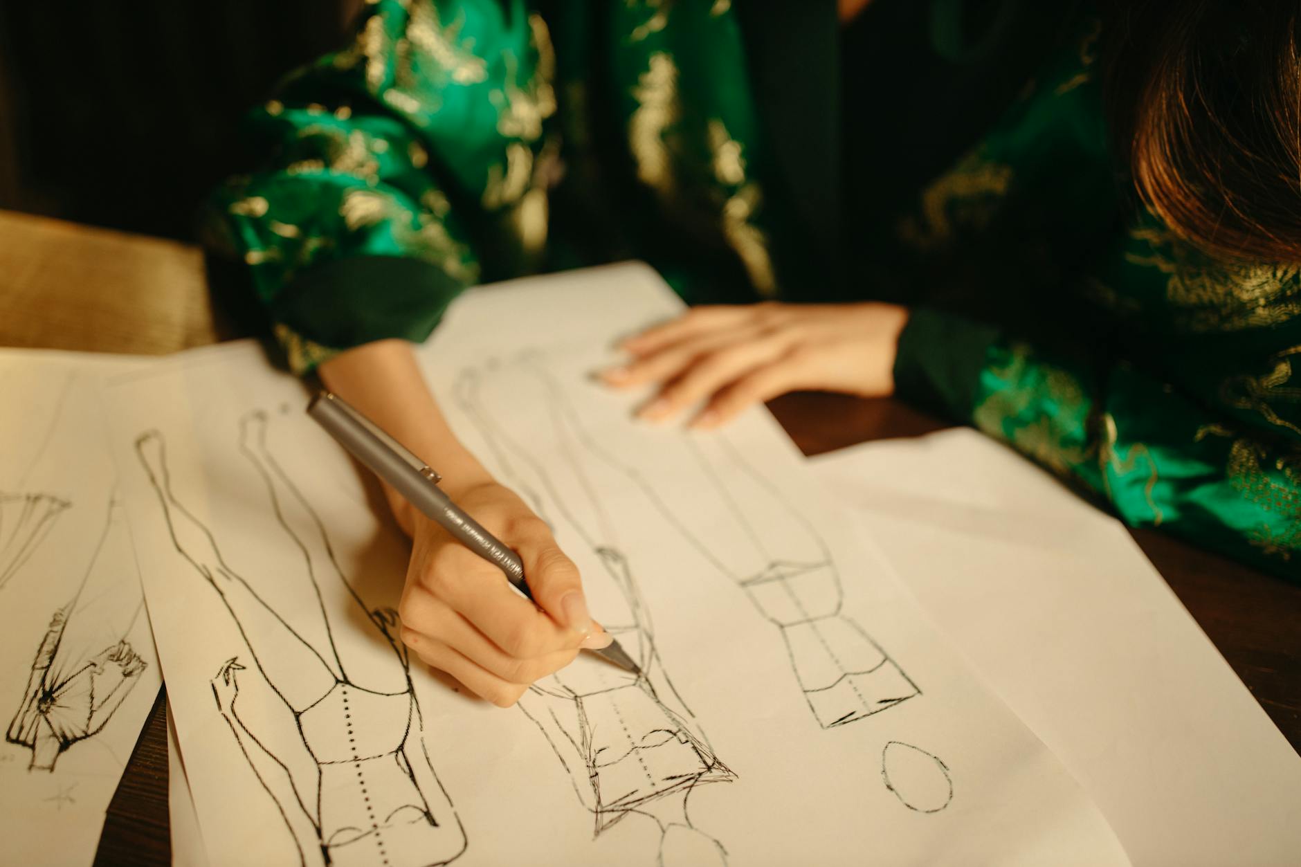 Fashion designer working on clothing sketches and design concepts at studio desk