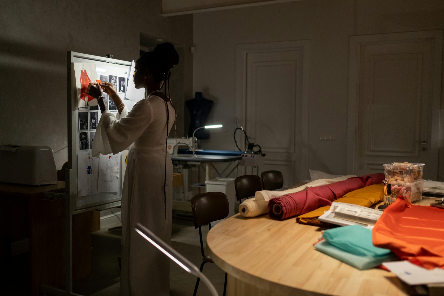 Fashion designer workspace with sketches, fabric samples, and clothing prototypes on display