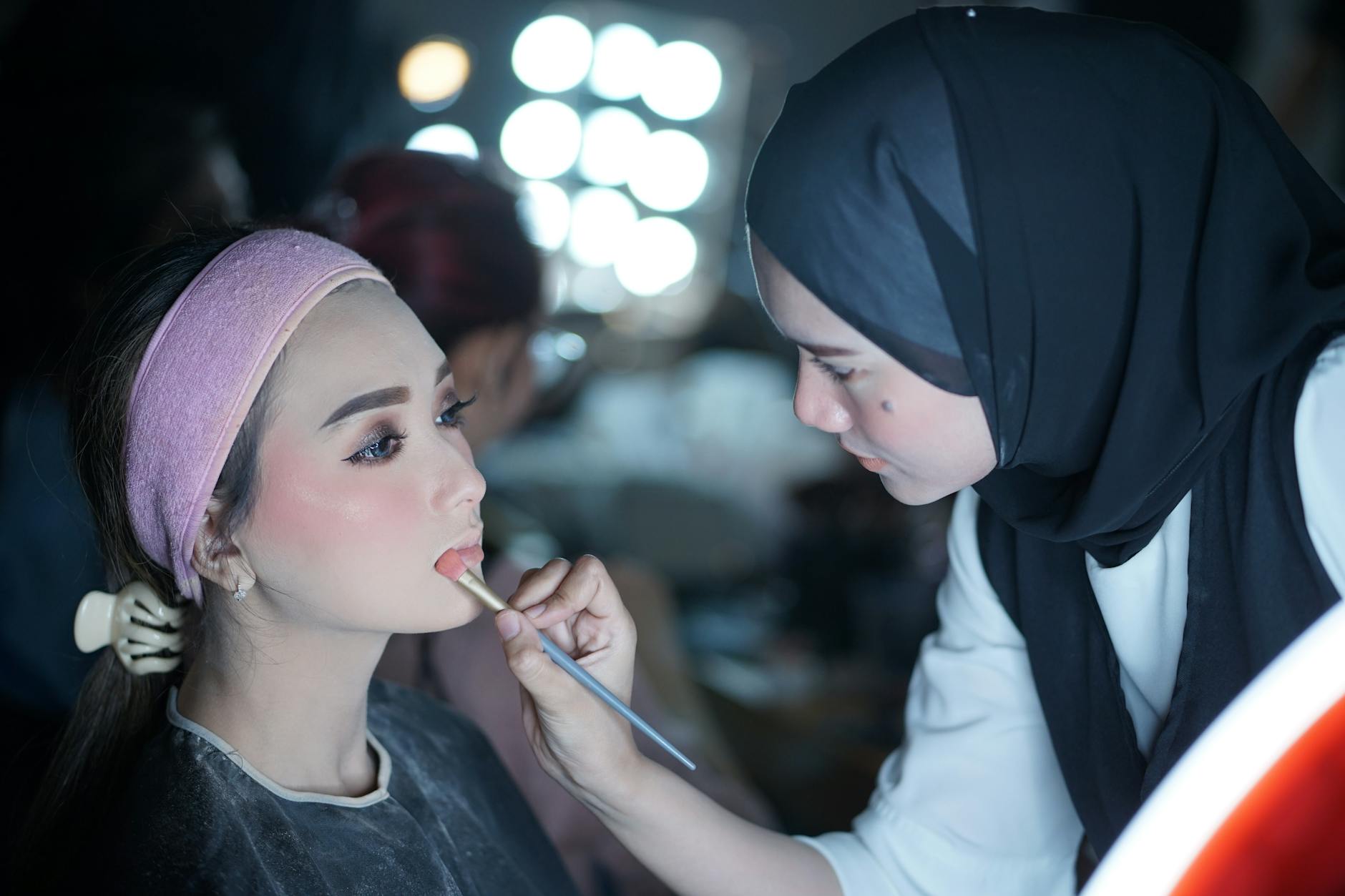 Professional makeup artist applying cosmetics to client in bright studio setting