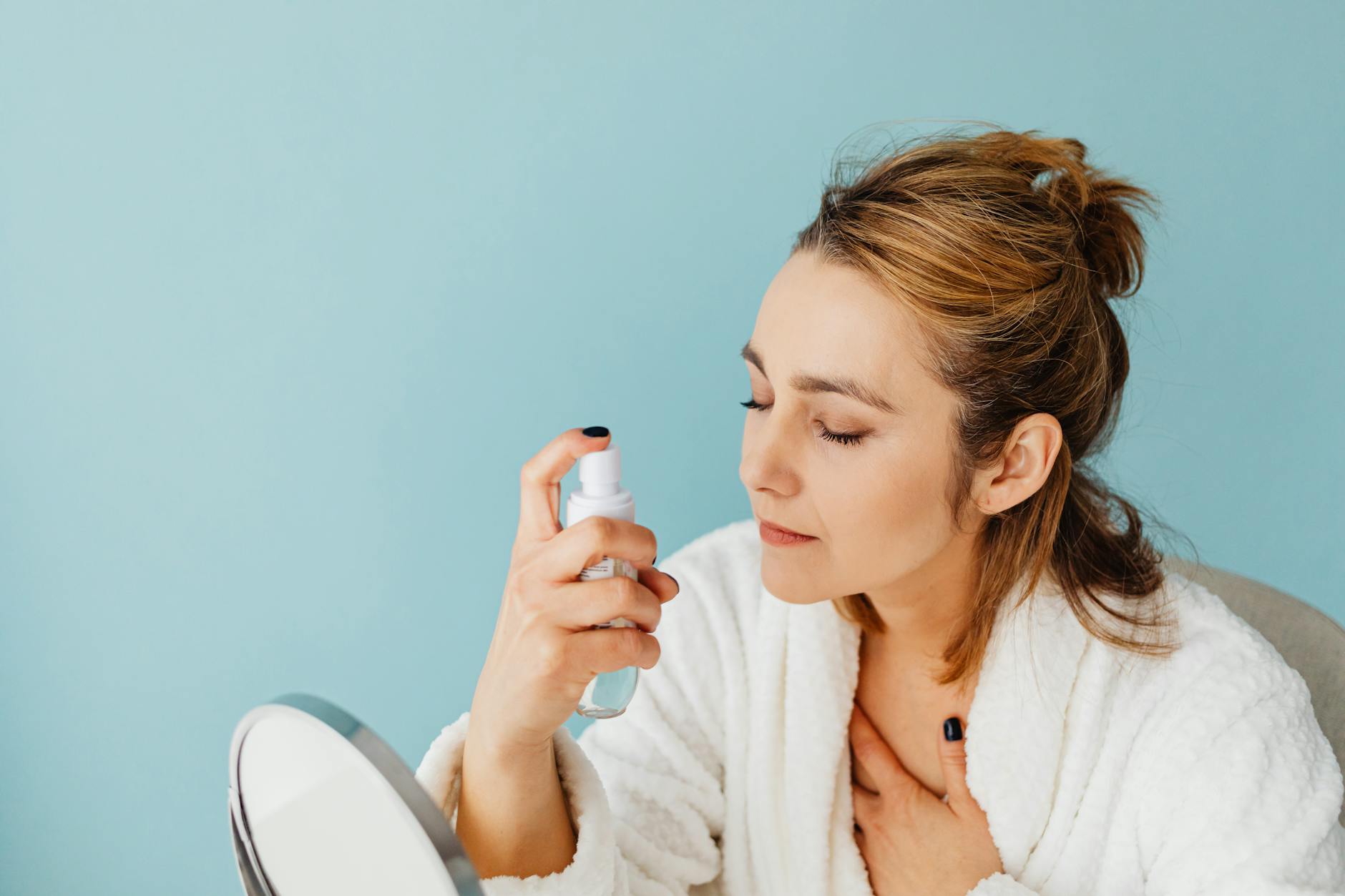 Woman applying skincare products in bathroom mirror as part of daily beauty routine