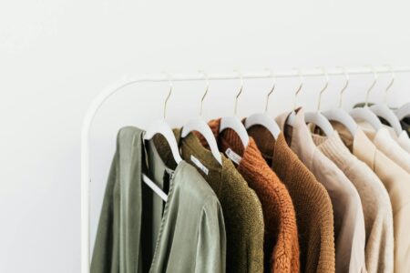 Minimalist beige and neutral-toned clothing hanging in a wardrobe, representing quiet luxury fashion aesthetic