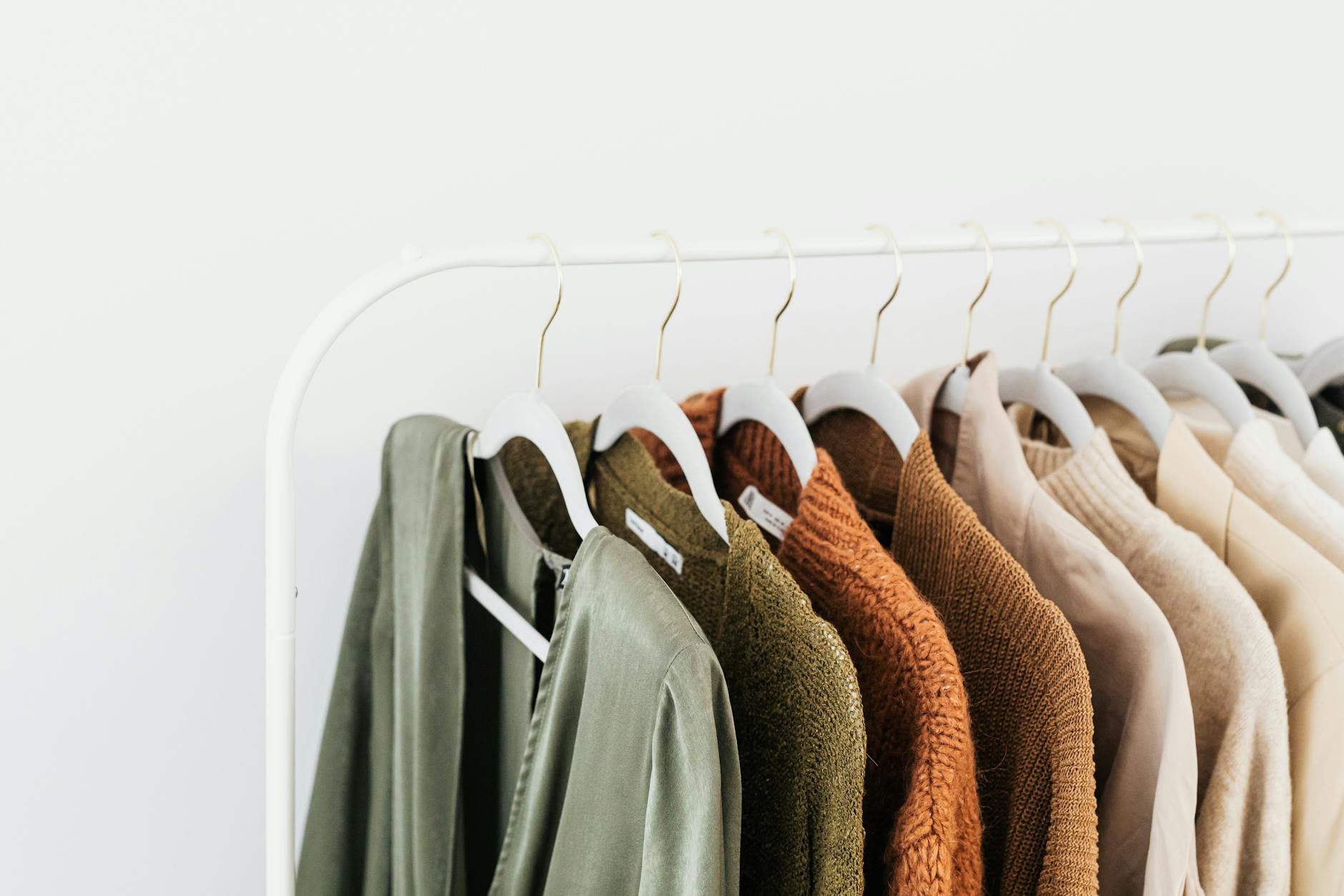 Minimalist beige and neutral-toned clothing hanging in a wardrobe, representing quiet luxury fashion aesthetic