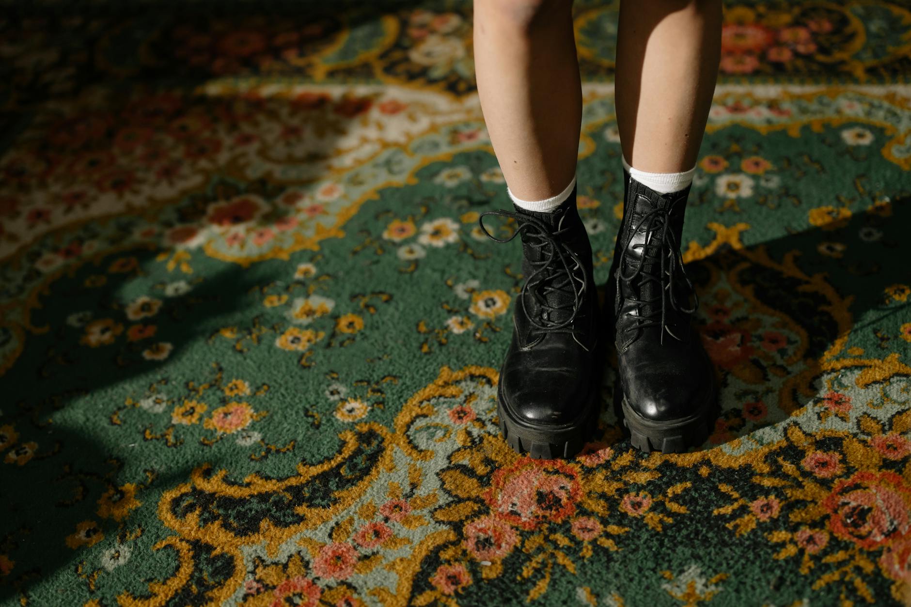 Close-up of brown leather ankle boots on a wooden floor, showing detailed stitching and worn patina