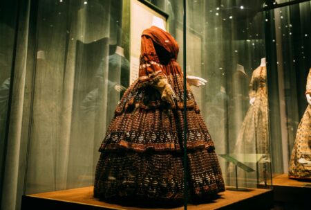 Designer Consignment Shops Are Outbidding Museums for Vintage Couture Elegant vintage designer dress displayed at an upscale auction house with bidding paddles visible