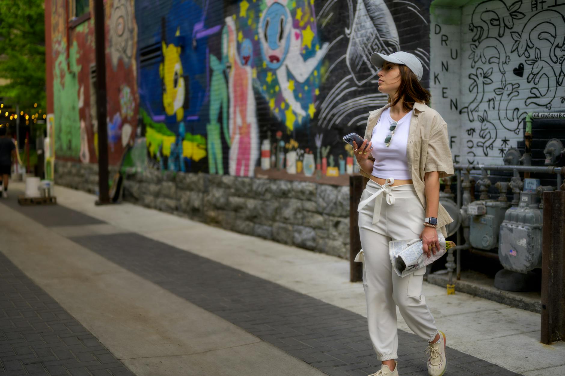 Person walking on a city sidewalk in tailored trousers and leather boots, captured from the waist down