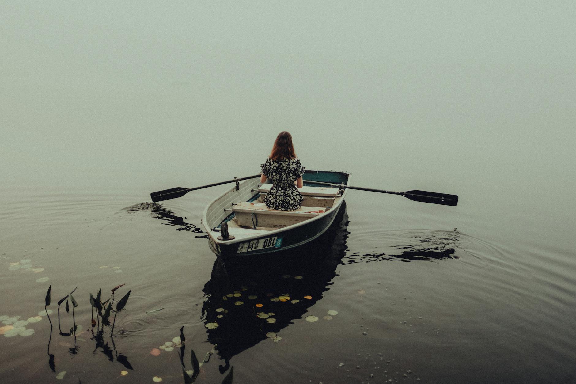 Rowers on calm water in the early morning, evoking the athletic origins of the rowing club aesthetic
