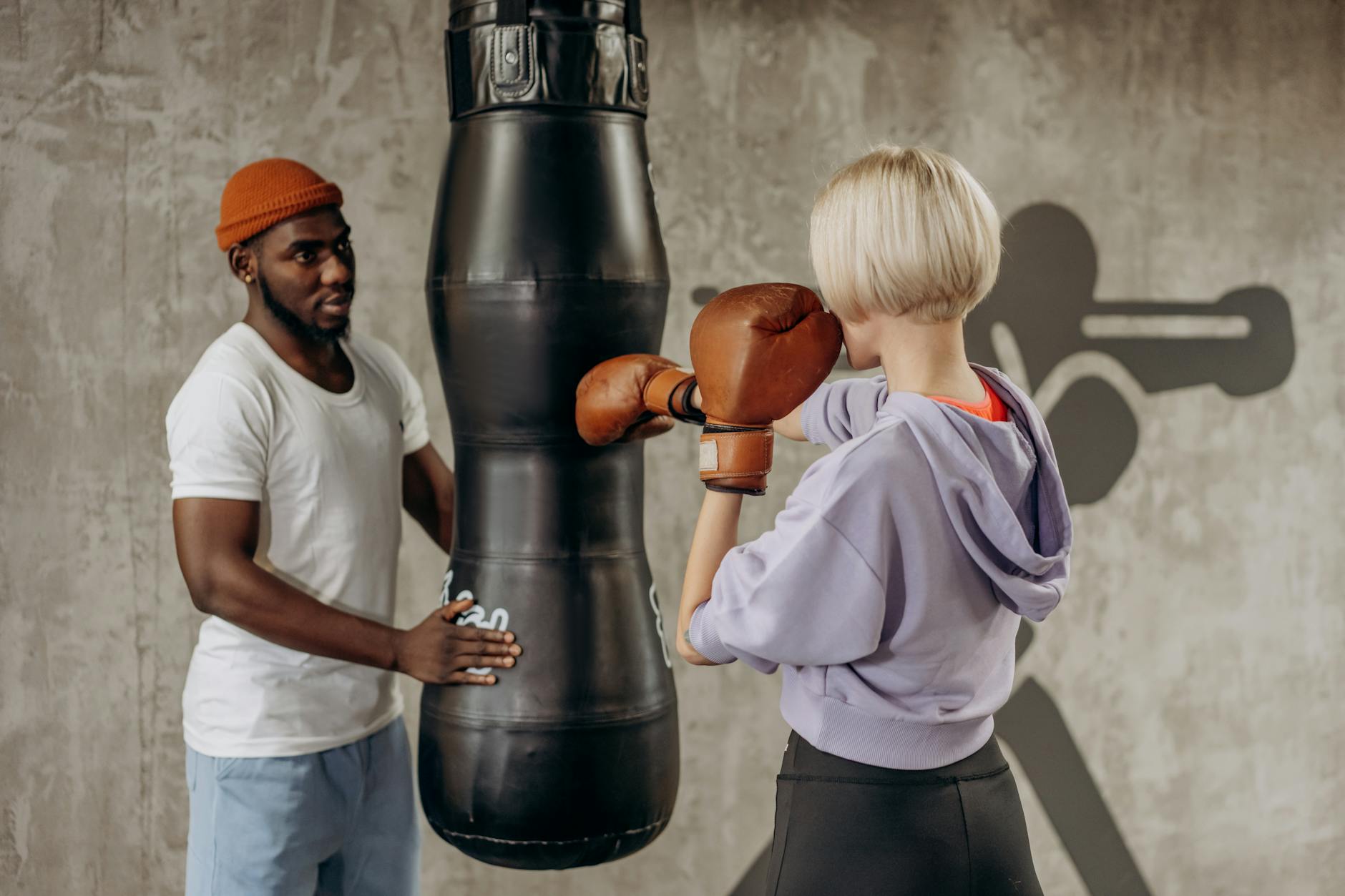 Woman training in a boxing gym wearing athletic satin shorts and gloves