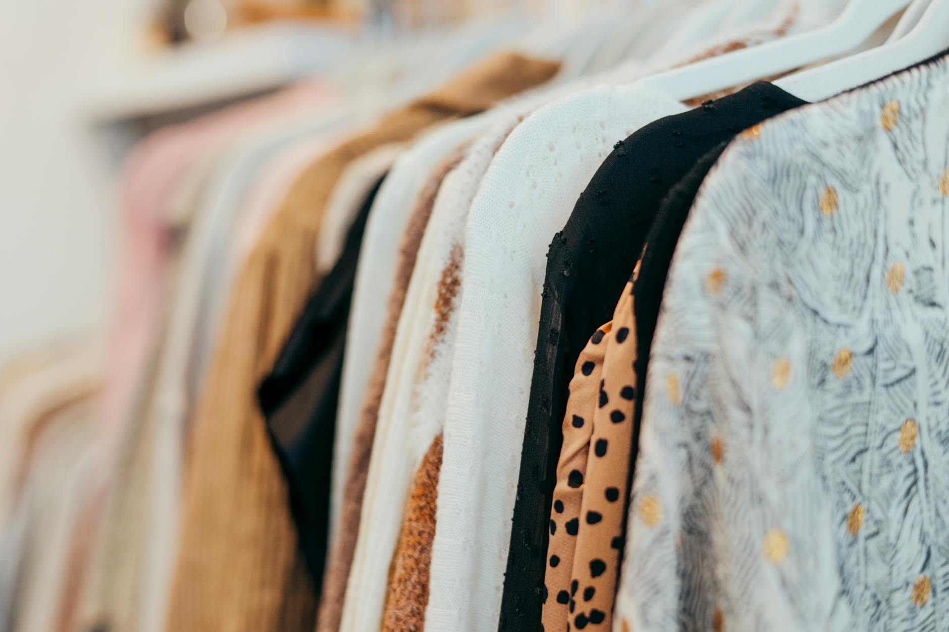 Person browsing through clothing racks in organized retail environment