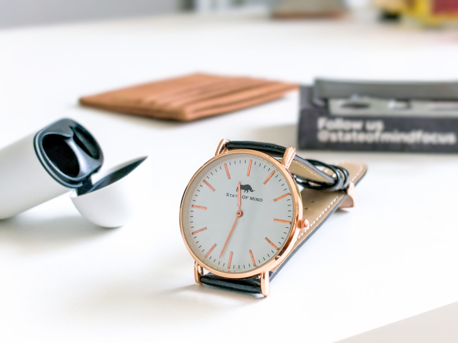 Close-up of minimalist leather wrist and tab accessories laid flat on neutral surface