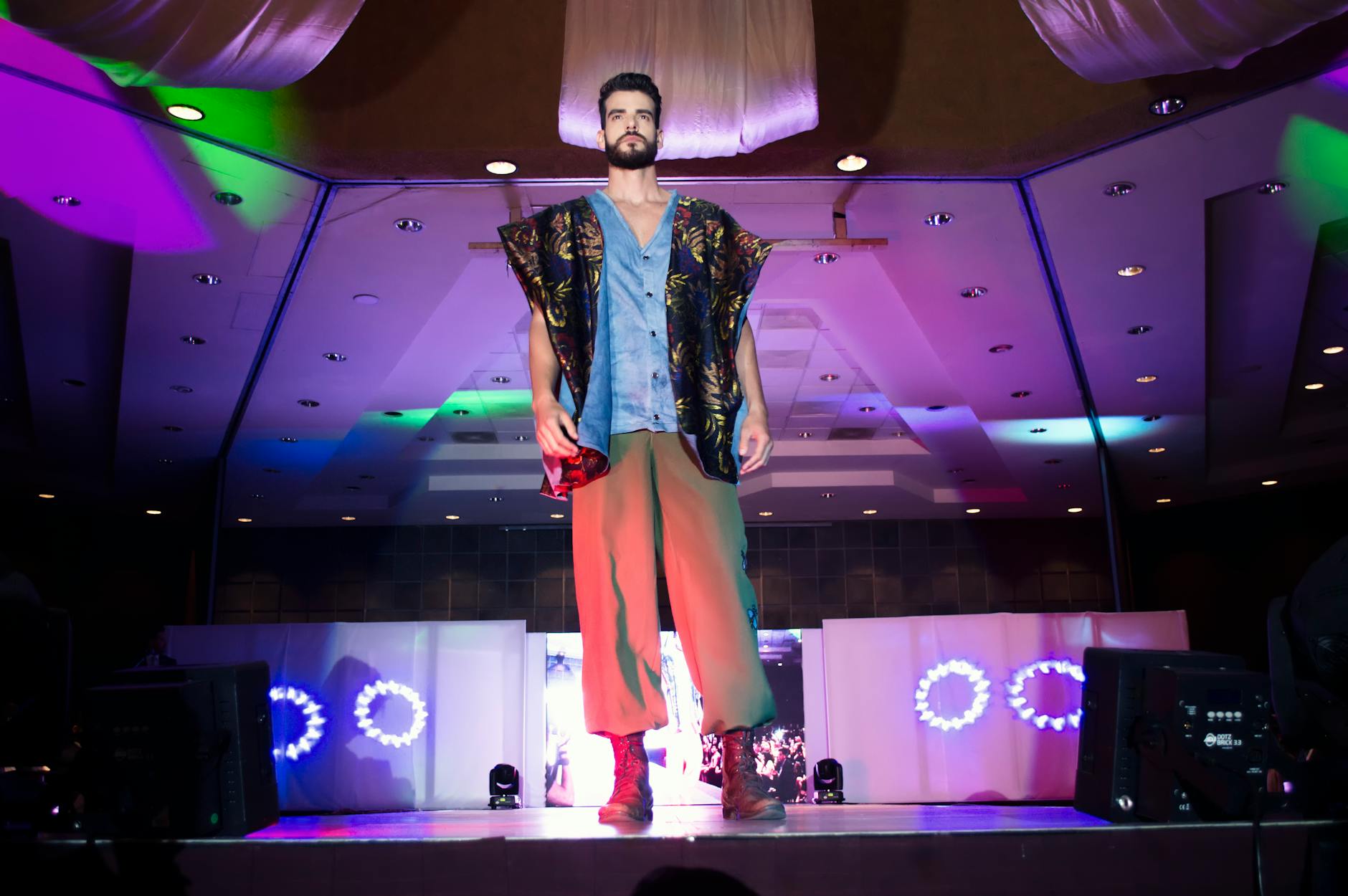 Model wearing a structured close-fitting cap on a fashion runway