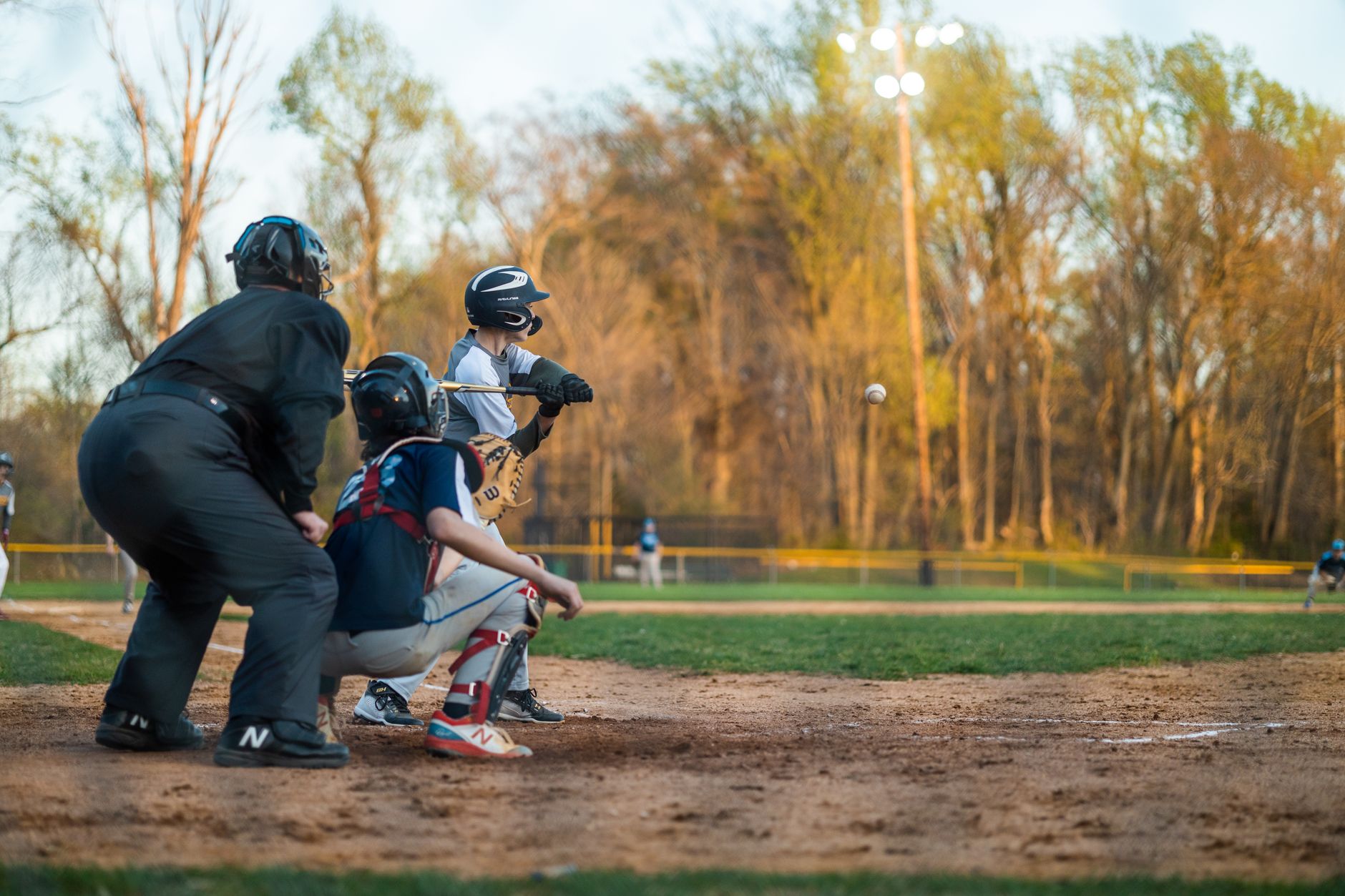 Baseball catcher in full protective gear including chest protector, shin guards, and cage mask