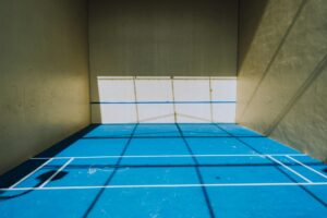 Empty squash court with white walls and wooden floor viewed from above