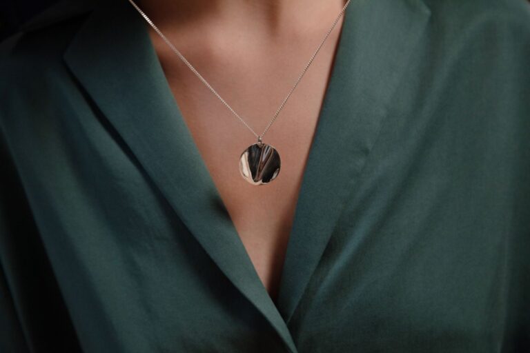 A delicate silver pendant necklace laid flat on a white surface