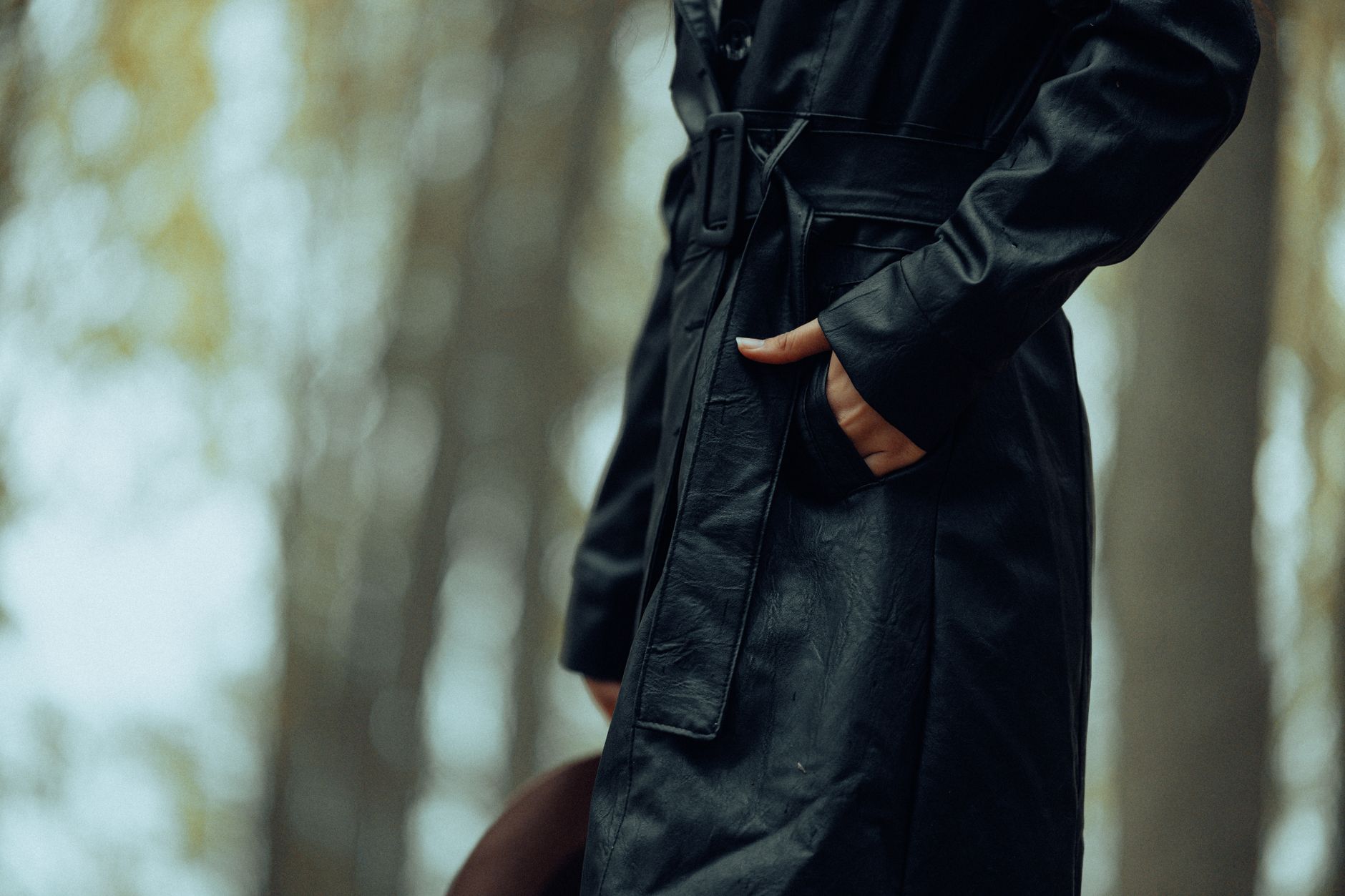 A person wearing a long waxed cotton coat outdoors, evoking equestrian workwear style