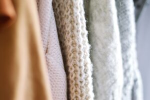 Neatly folded polo wrap and quarter-zip knit layers in neutral tones arranged on a flat surface