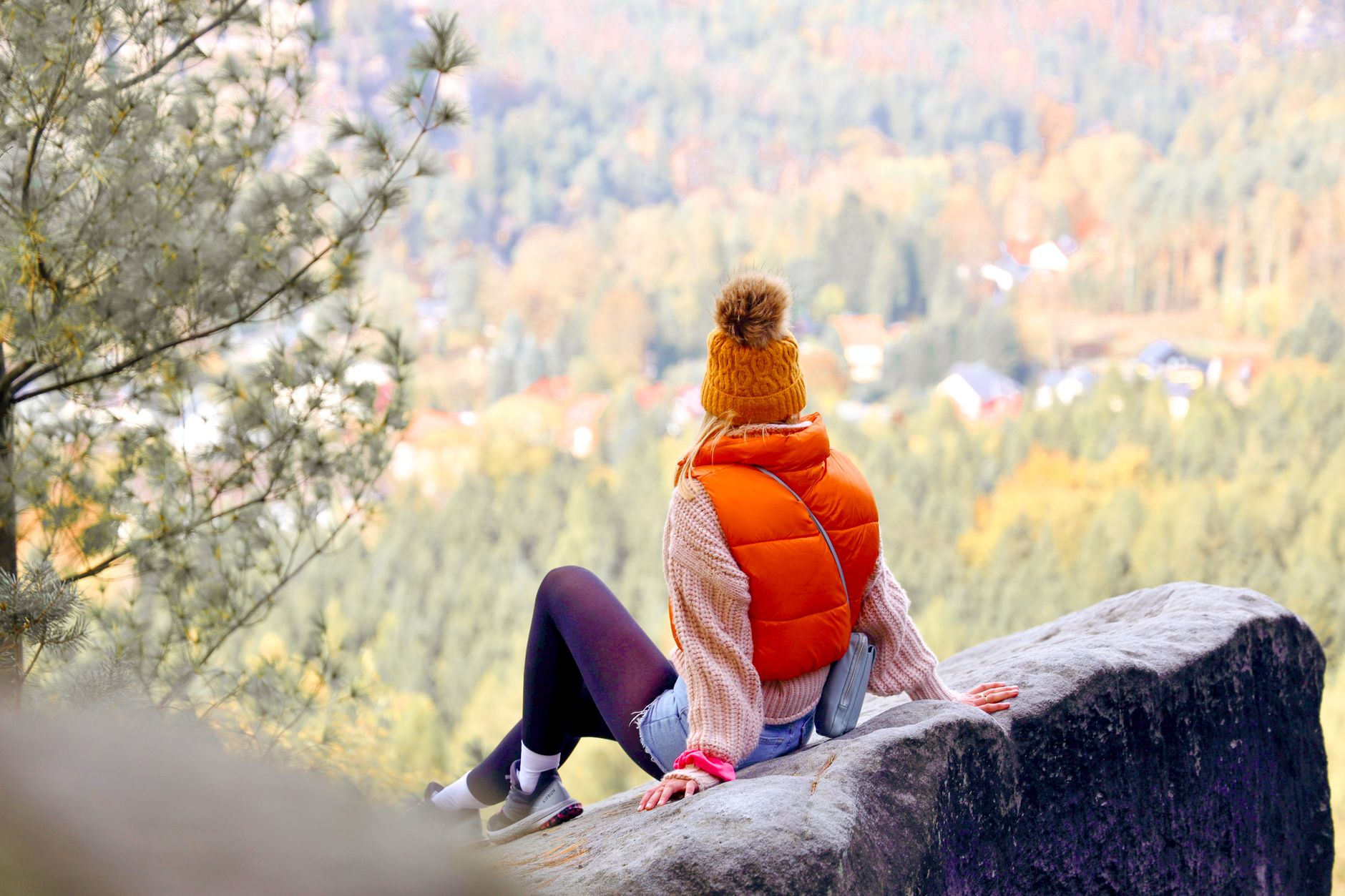 A person wearing a fitted quilted gilet over a turtleneck sweater in an outdoor setting