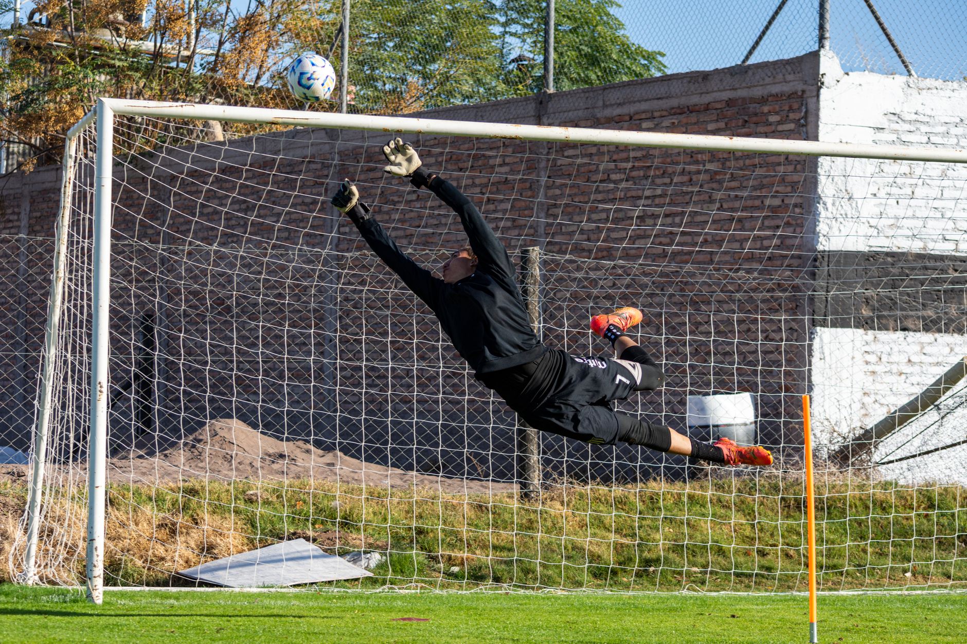 Close-up of structured goalkeeper gloves with grip panel detailing laid flat on a dark surface