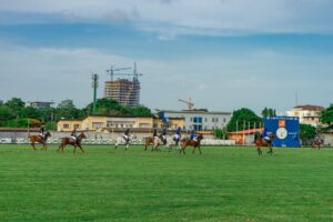 Polo players on horseback wearing traditional white breeches and leather protective gear during a match