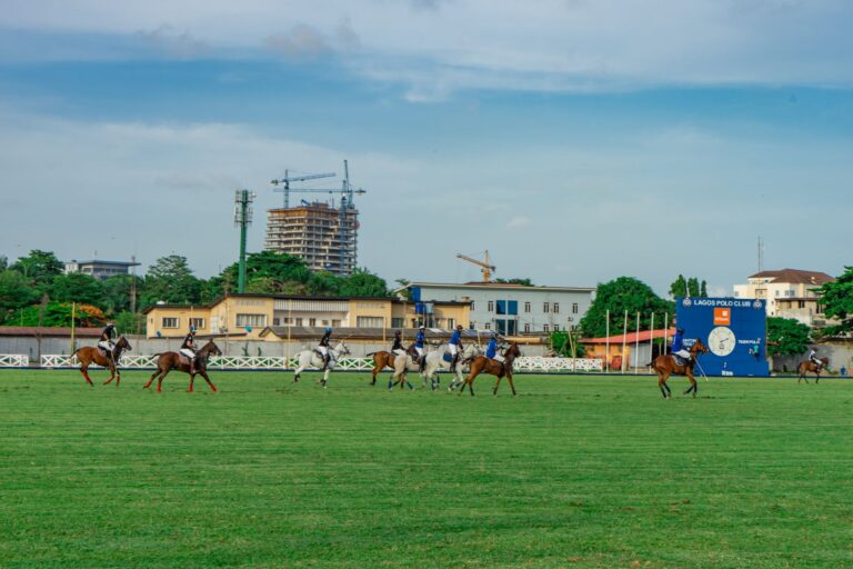 Polo players on horseback wearing traditional white breeches and leather protective gear during a match