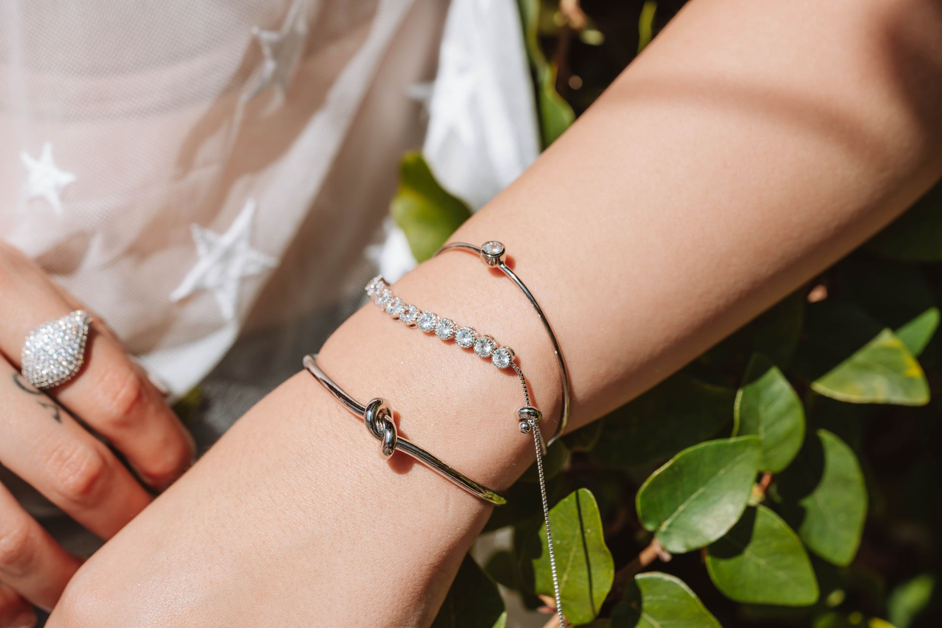 Stacked fabric and wrap bracelets worn on a wrist with mixed hardware finishes