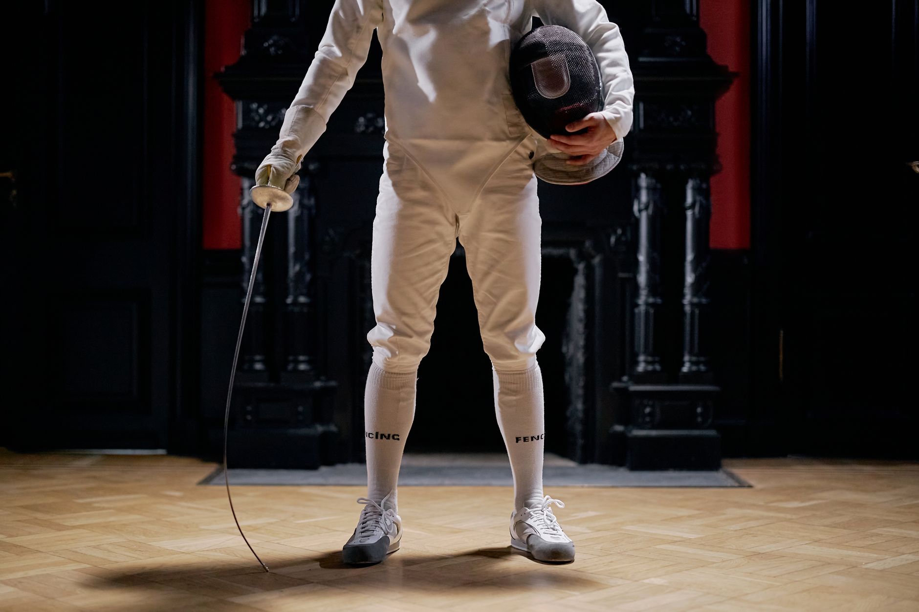 Fencing protective jacket and equipment laid out, showing dense quilted paneling and reinforced construction