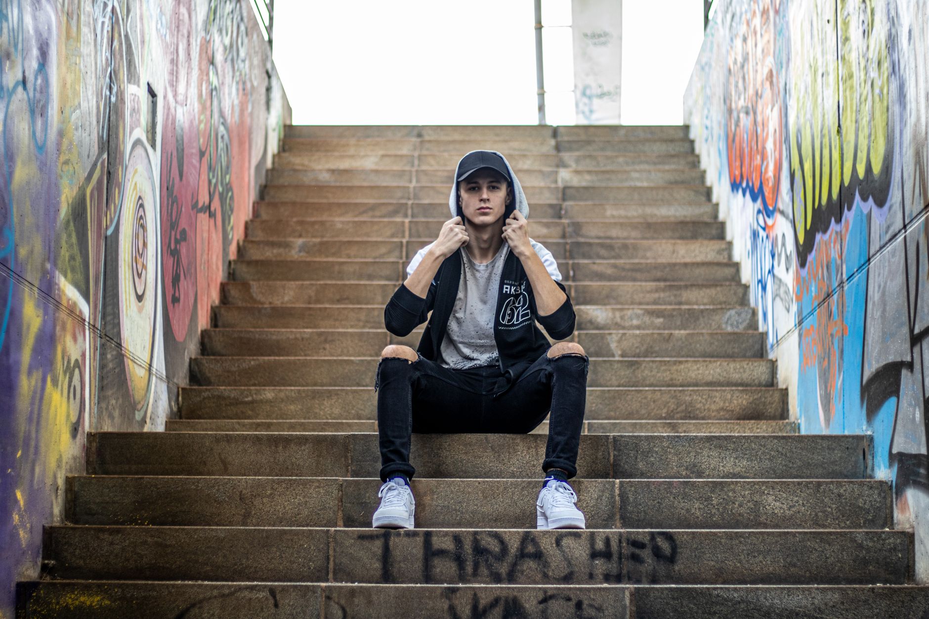 Person wearing layered streetwear outfit with oversized base layer and mesh vest in a city setting