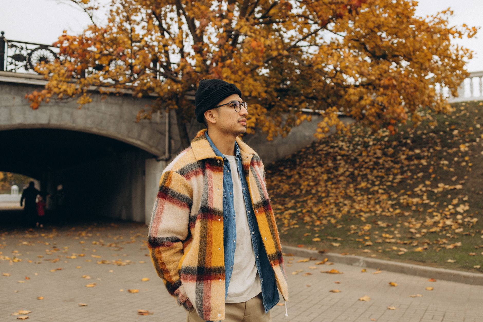 A model wearing layered utility streetwear with a vest over a long-sleeve base layer and wide-leg trousers