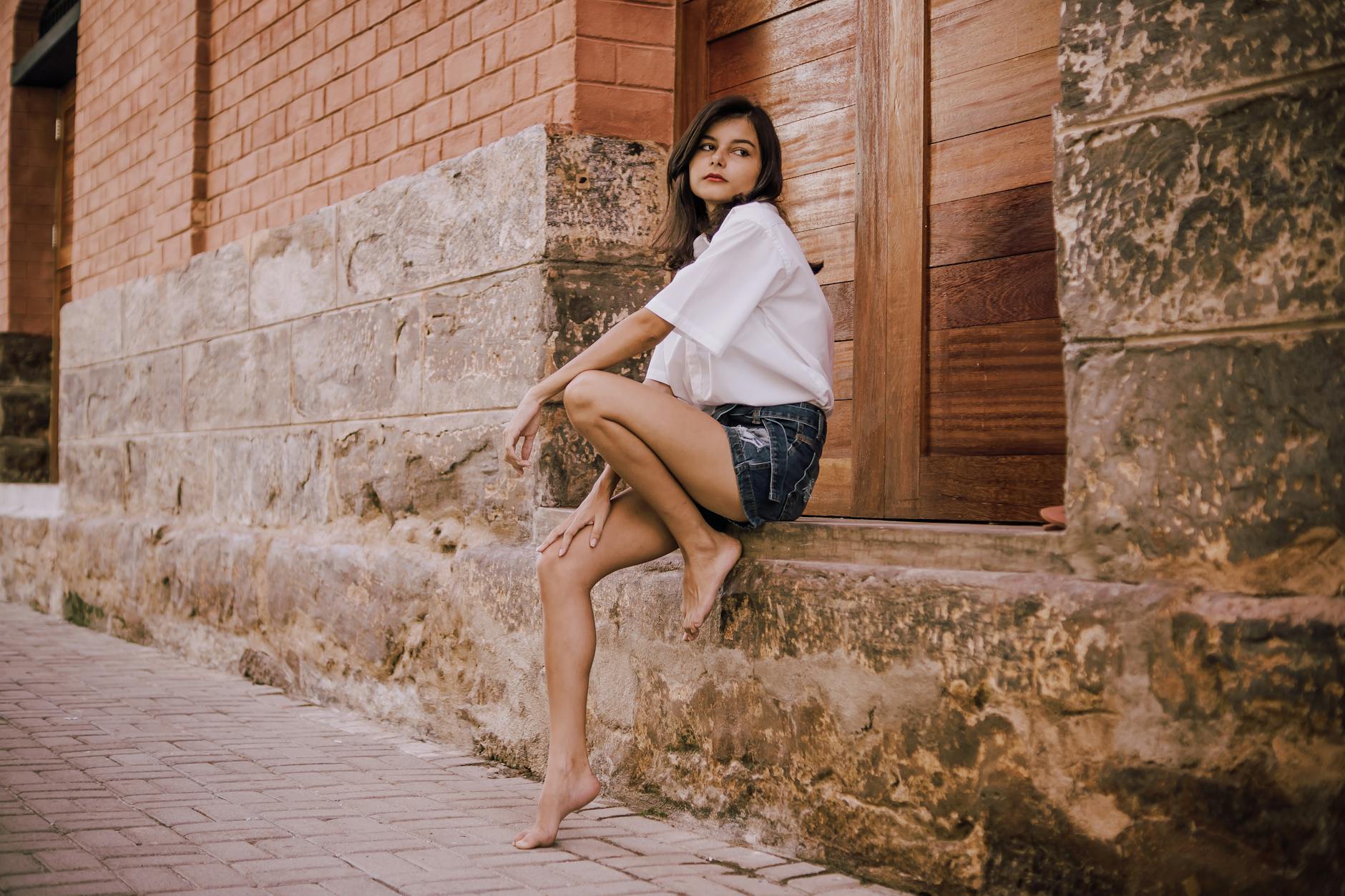 A person dressed casually in a minimal summer outfit with sneakers and a short dress