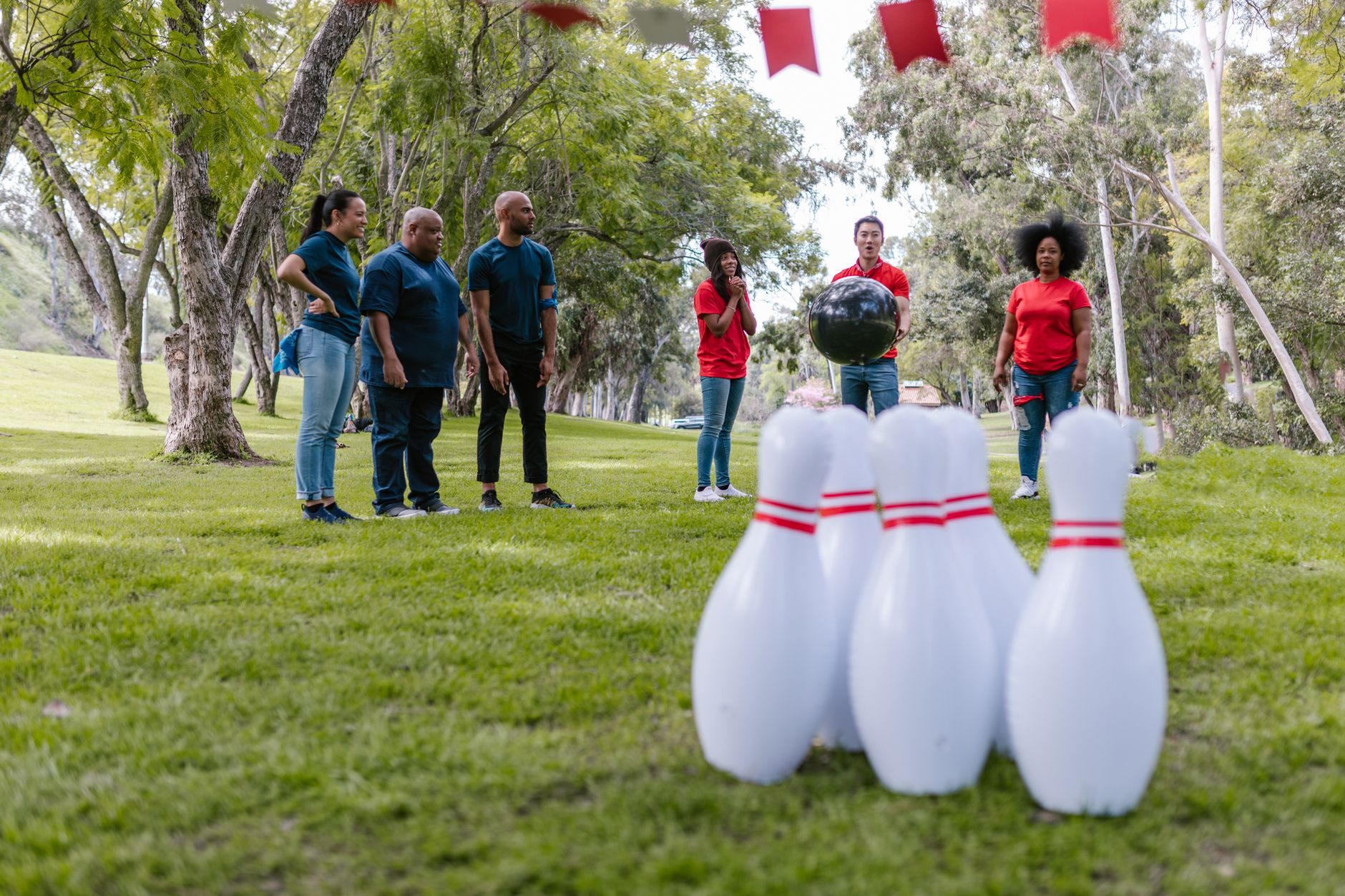 Players on a lawn bowls green wearing traditional cream club attire and flat canvas shoes