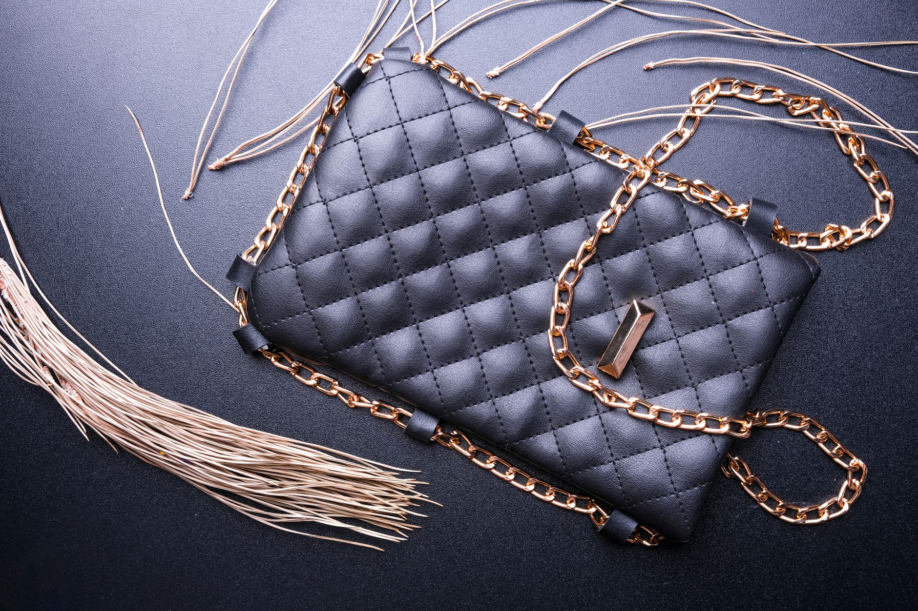 Structured luxury handbag with rolled leather top handle against a neutral background