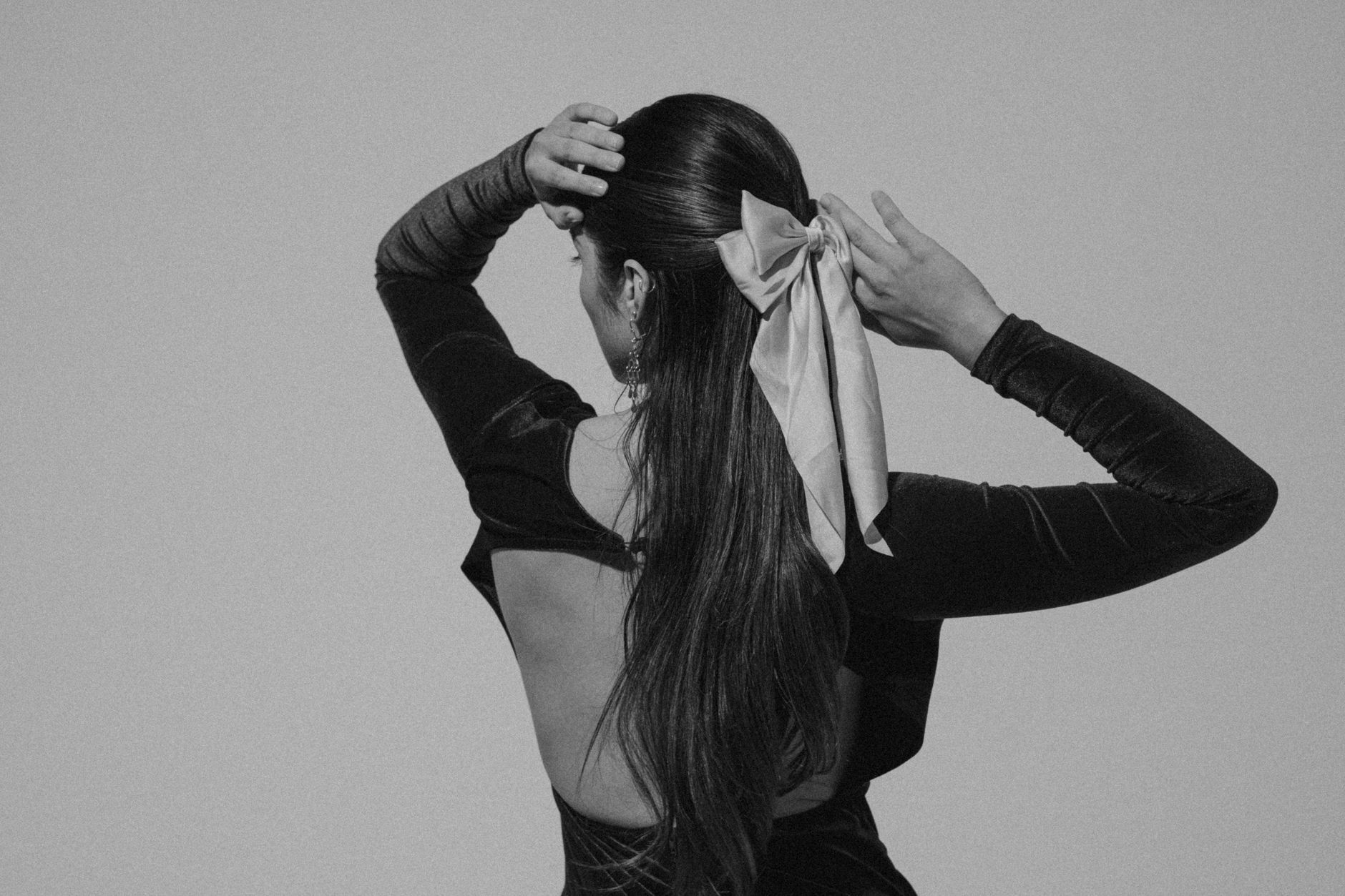 Simple, clean ponytail secured with a small undecorated band against a neutral background
