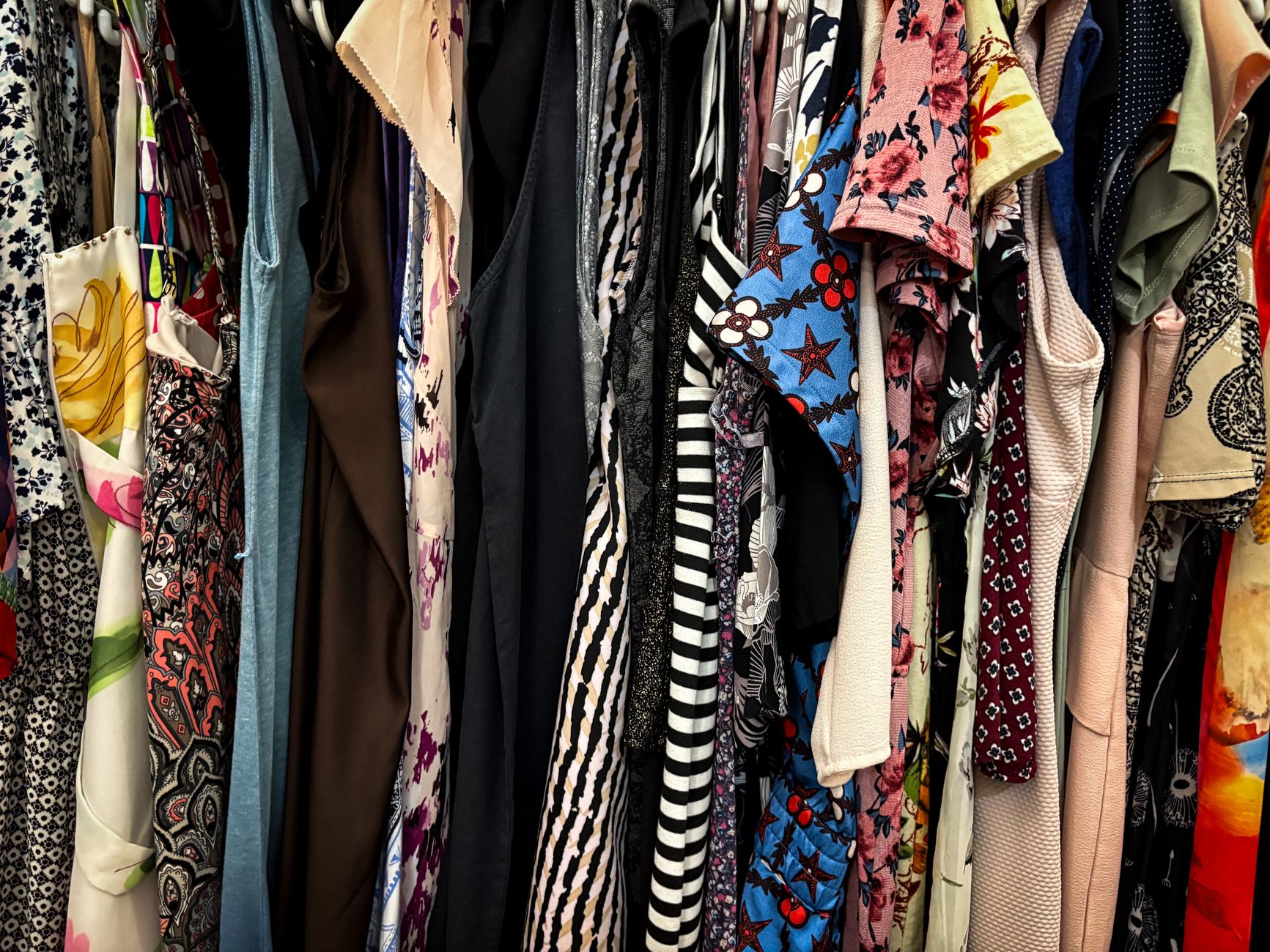 A rack of vintage American sportswear garments organized by color in a resale setting