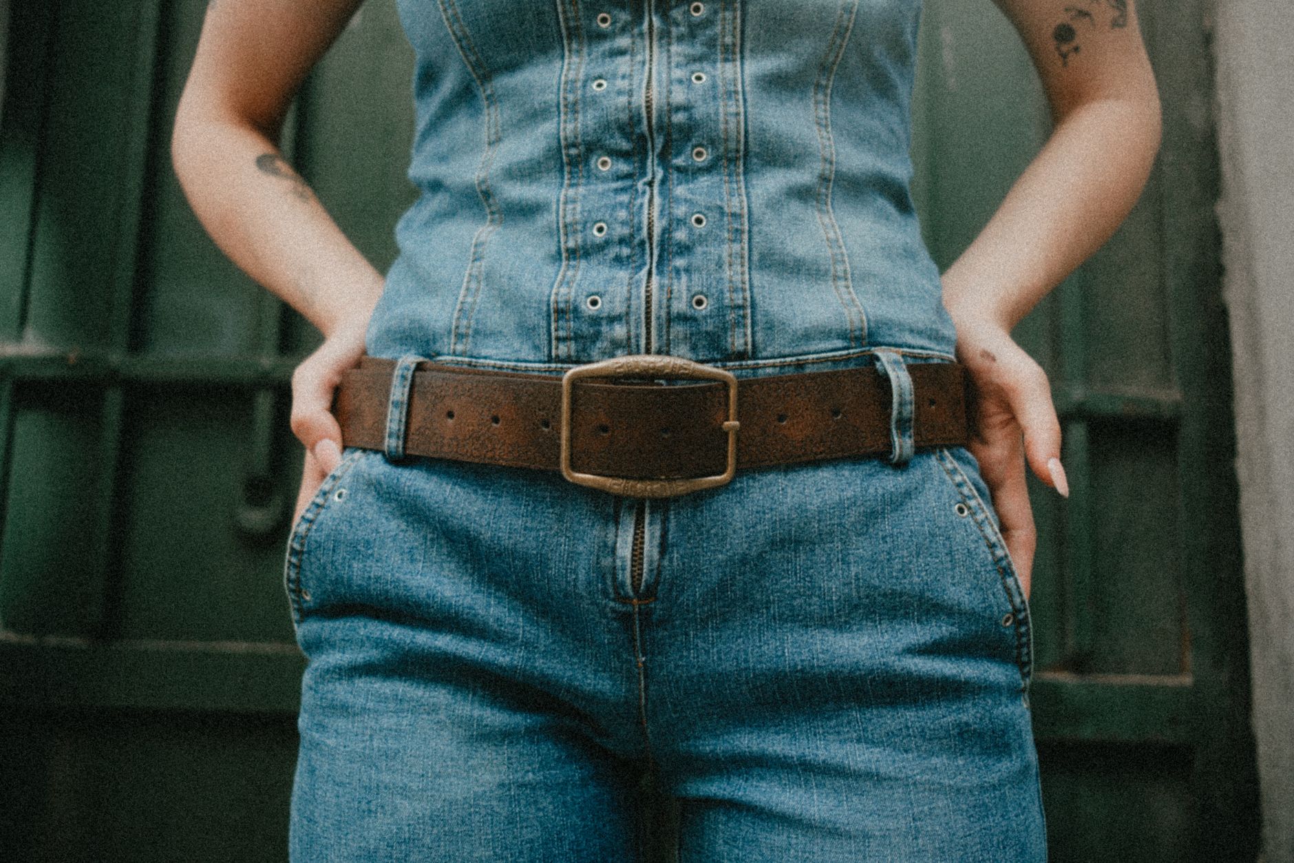 Model wearing a wide statement belt with an oversized metal buckle as a focal point of a tailored outfit