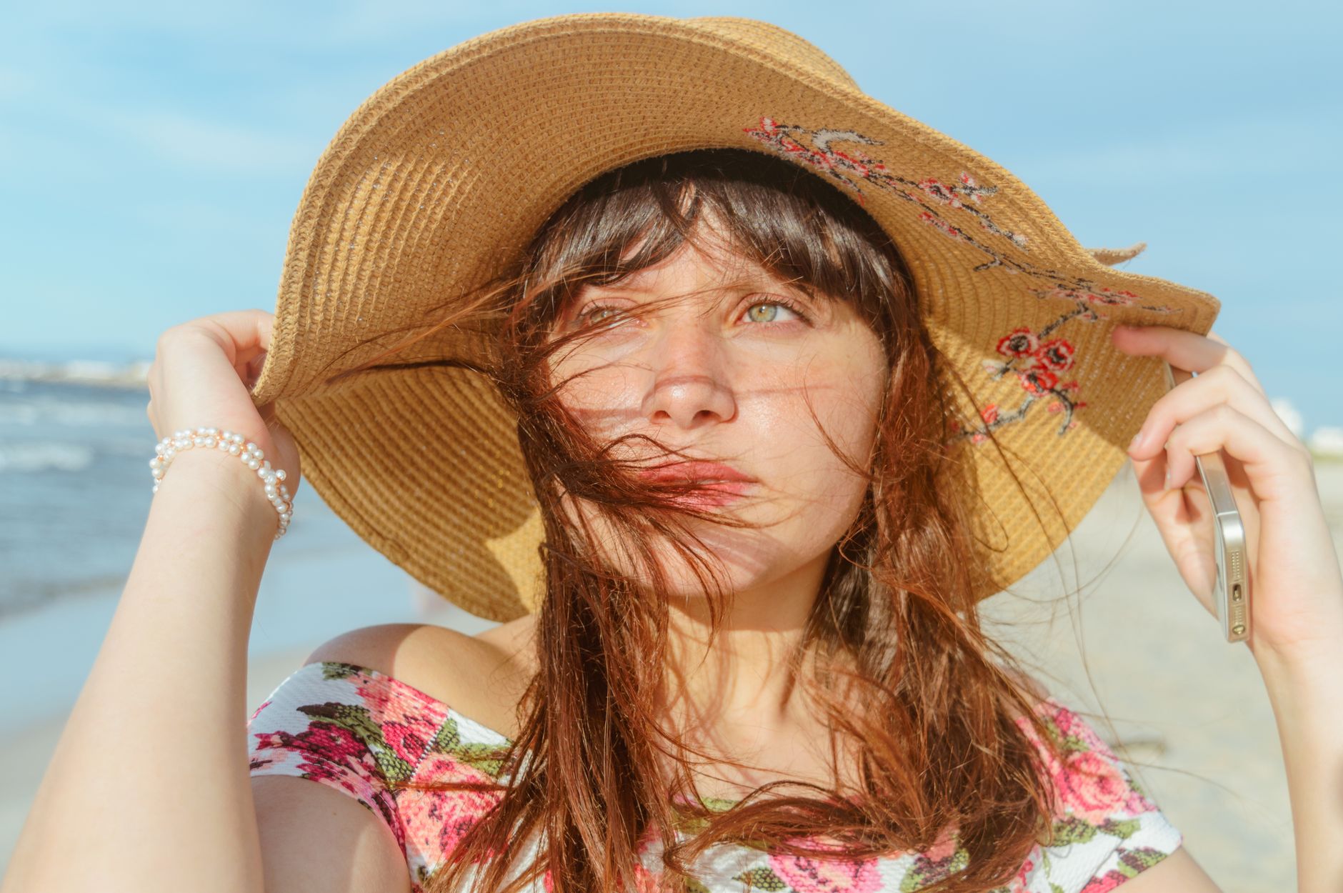 Wide-brimmed straw hat resting beside white tailored clothing outdoors