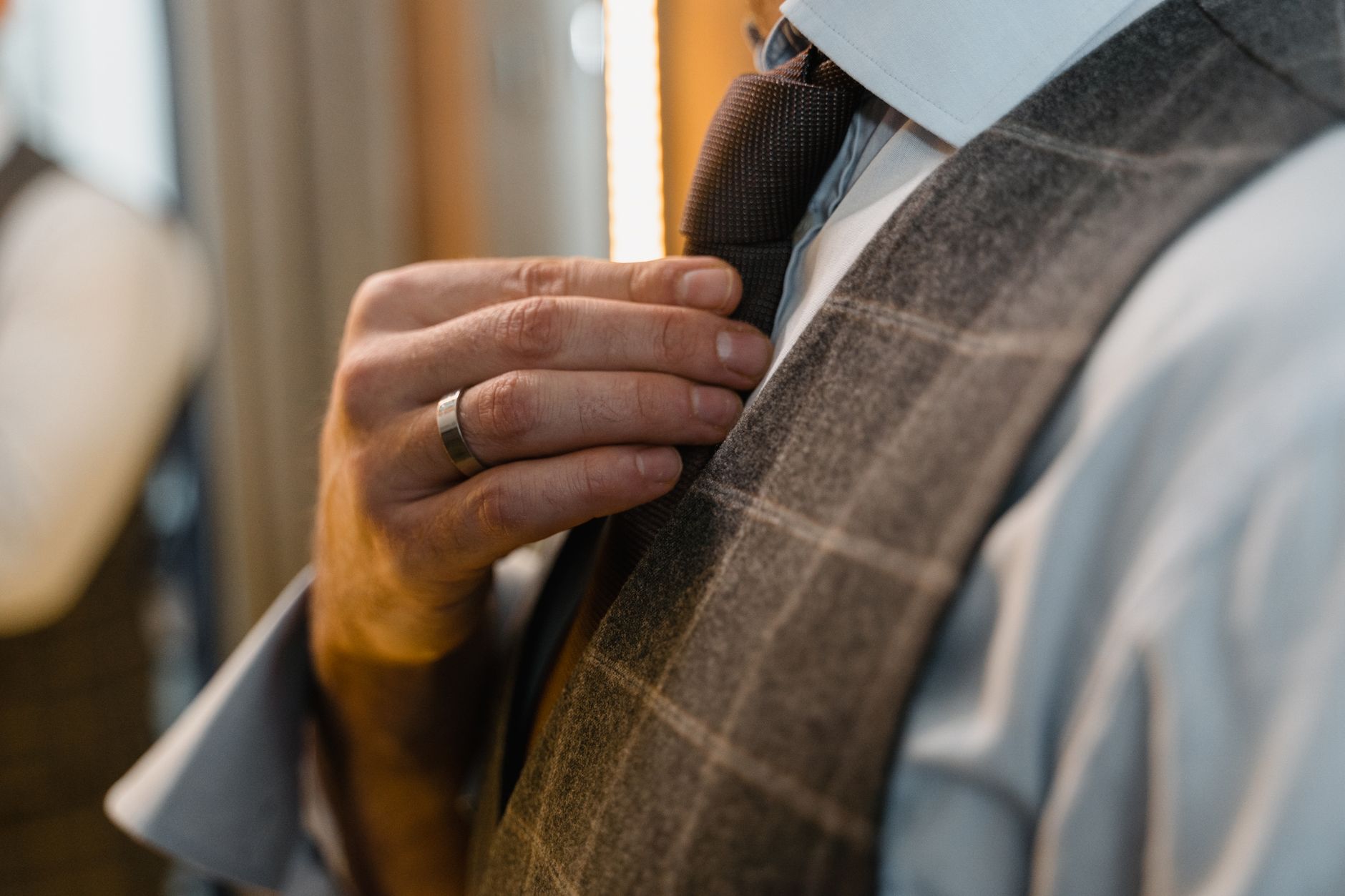 Close-up of a silver engraved tie clip resting on a white dress shirt collar