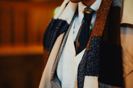 Polo Club Stock Ties Are Quietly Knotting Into Minimalist Neckwear Drops A neatly folded white stock tie laid flat, showing its structured horizontal shape and simple bar pin