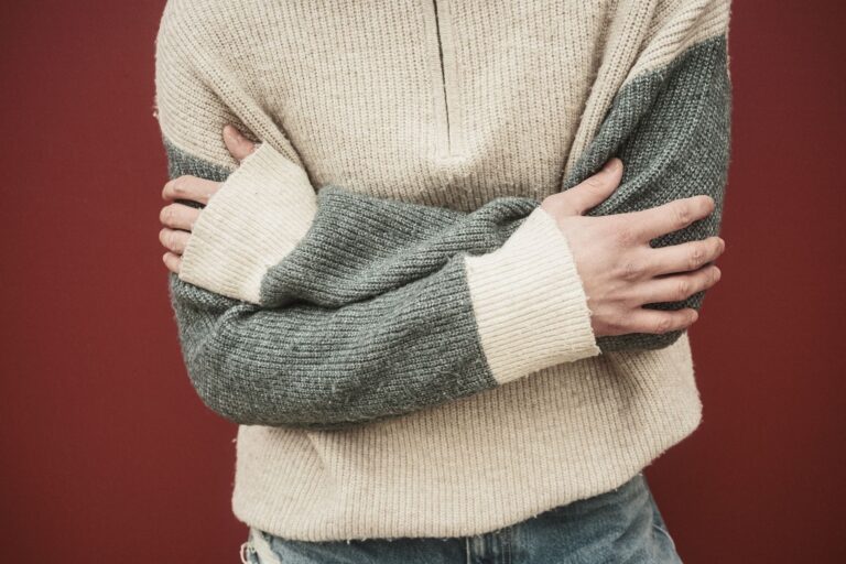 Rowing Club Blade Colours Are Bleeding Into Resort Stripe Knitwear Colorful striped knit pullover folded on a light surface, showing bold horizontal stripe patterns in navy, cream, and gold