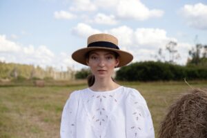 A classic flat-brimmed straw boater hat displayed against a light background
