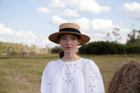 A classic flat-brimmed straw boater hat displayed against a light background
